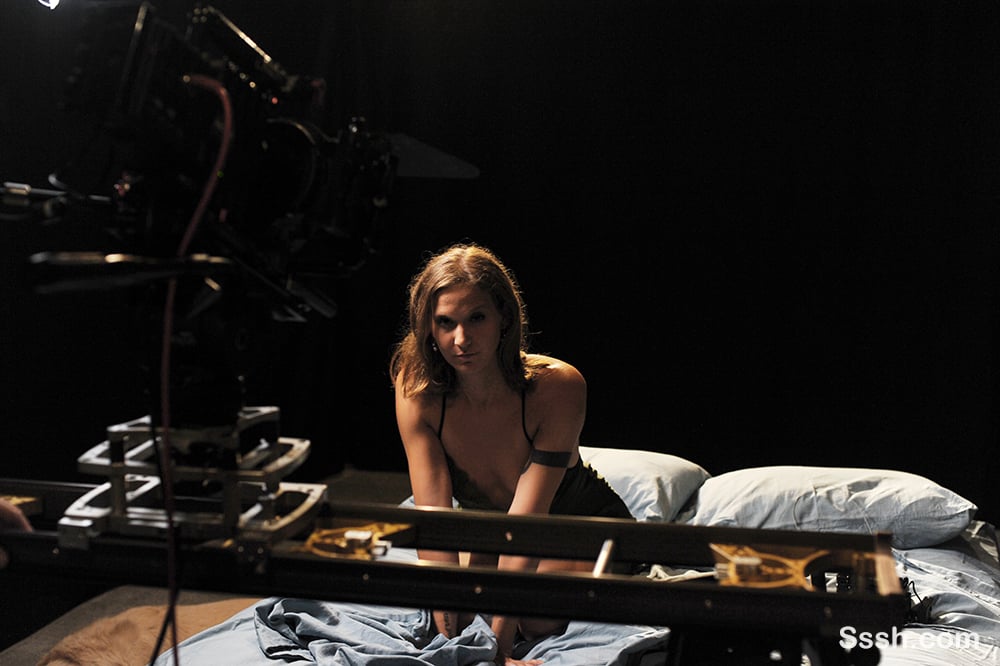 BTS behind the scenes on a Sssh set. Young women sits on a bed. A camera is on a slider
