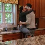 A women sits on the kitchen counter kissing a man passionately